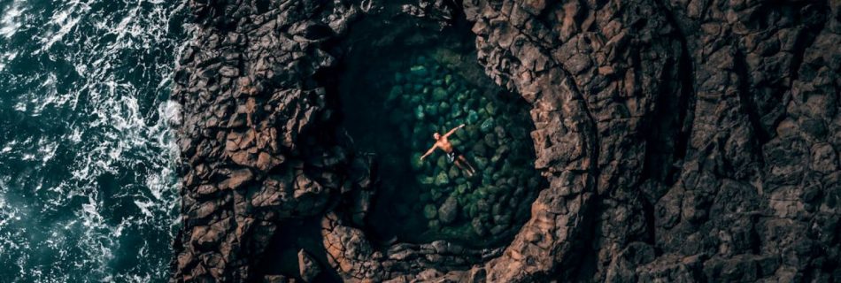 Rock Pooling Cornwall - Person swimming in pool in rock near wavy ocean in daytime