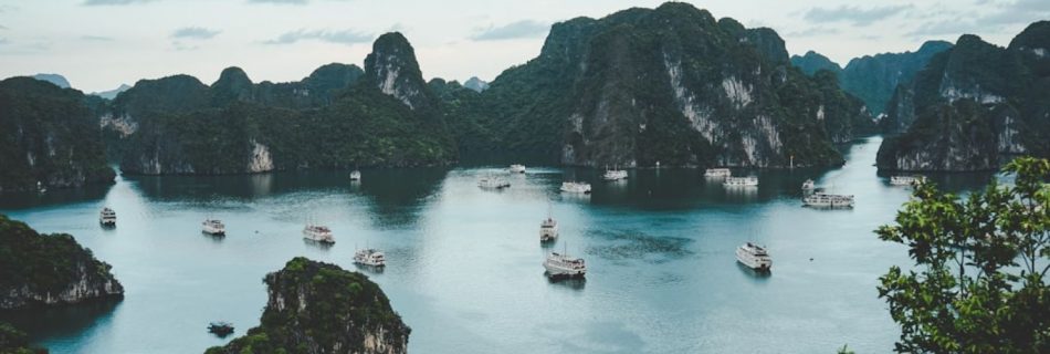 Boat Tour - high-angle photography of boats on water near hill during daytime