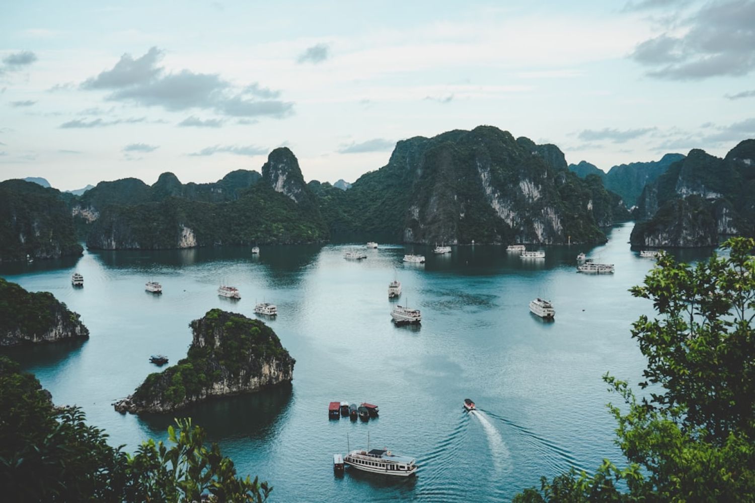 Boat Tour - high-angle photography of boats on water near hill during daytime