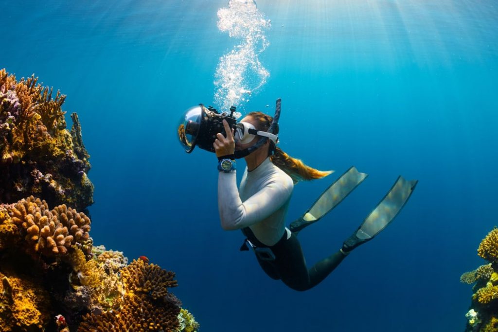 Scuba Diving - a woman scubas in the ocean with a camera