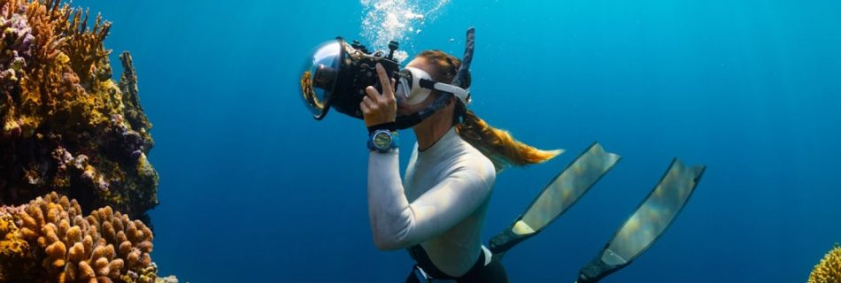 Scuba Diving - a woman scubas in the ocean with a camera