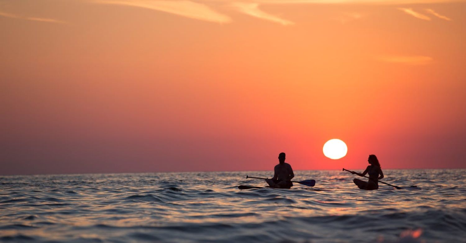 Paddleboard - Man and Woman Boat Rowing in Sea during Golden Hour